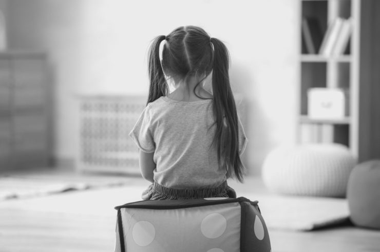 Loneliness in leadership blog cover. Photo is of a little girl facing away at the wall, sat on a big toy dice.