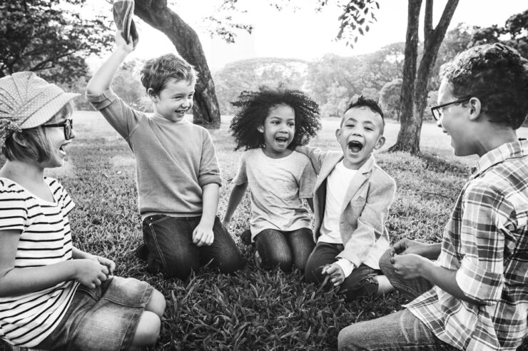 Group of children sat on the grass. Photo is in black and white and is for the inclusive hiring process blog