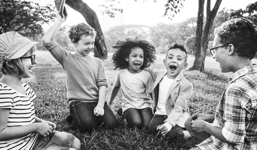 Group of children sat on the grass. Photo is in black and white and is for the inclusive hiring process blog