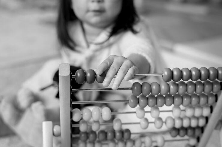 black and white close up photo of Little girl playing abacus for counting practice. Cover photo for IR35 blog.