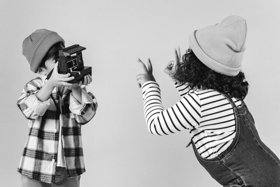 Black and white photo of a child having their photo takent by another child. Cover image for the LinkedIn profile blog