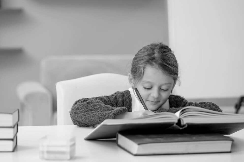 Black & white image of a child doing their homework at a desk. Cover image for the 'how to prepare for a tech interview' blog.