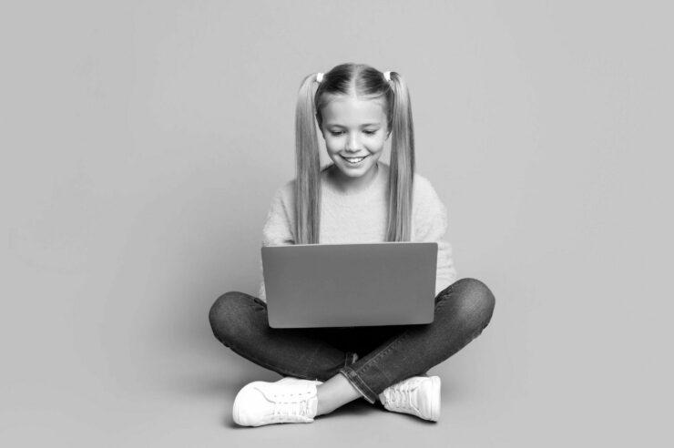 Girl sat cross-legged on the floor with a laptop on her lap. Cvoer image for the 'What are the best tech job search sites to bookmark' blog