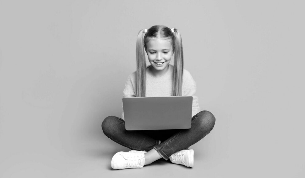 Girl sat cross-legged on the floor with a laptop on her lap. Cvoer image for the 'What are the best tech job search sites to bookmark' blog