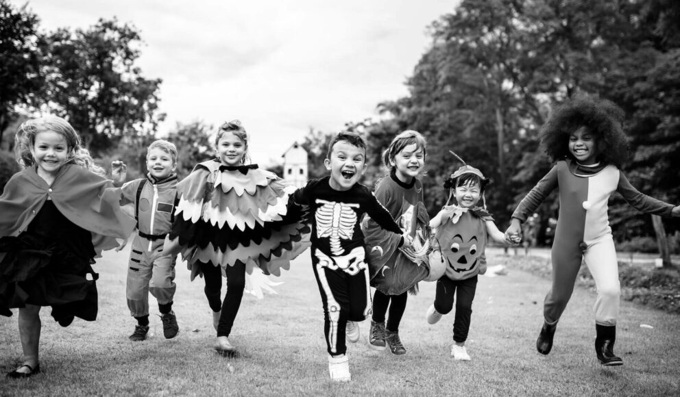 Black and white image of a group of kids running in a field wearing halloween costumes. Image is cover image for the inclusive recruitment practices blog.