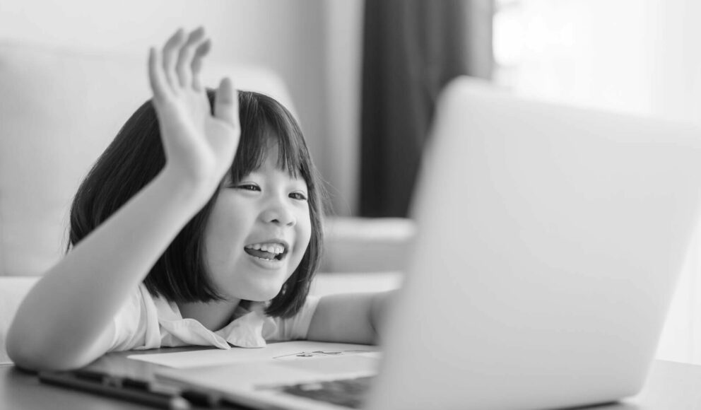 Black and white photo of a child on a video call. Cover image for the Remote company culture blog.