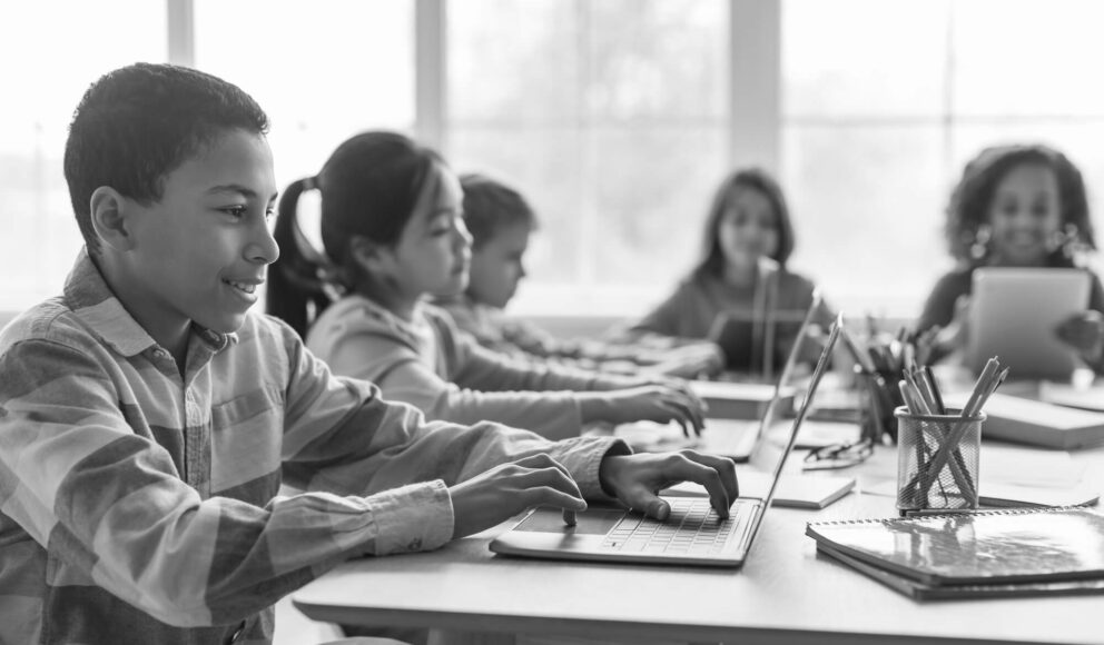 Black and white photo of a group of kids stat at a desk. Blog cover image for the candidate experience guide.