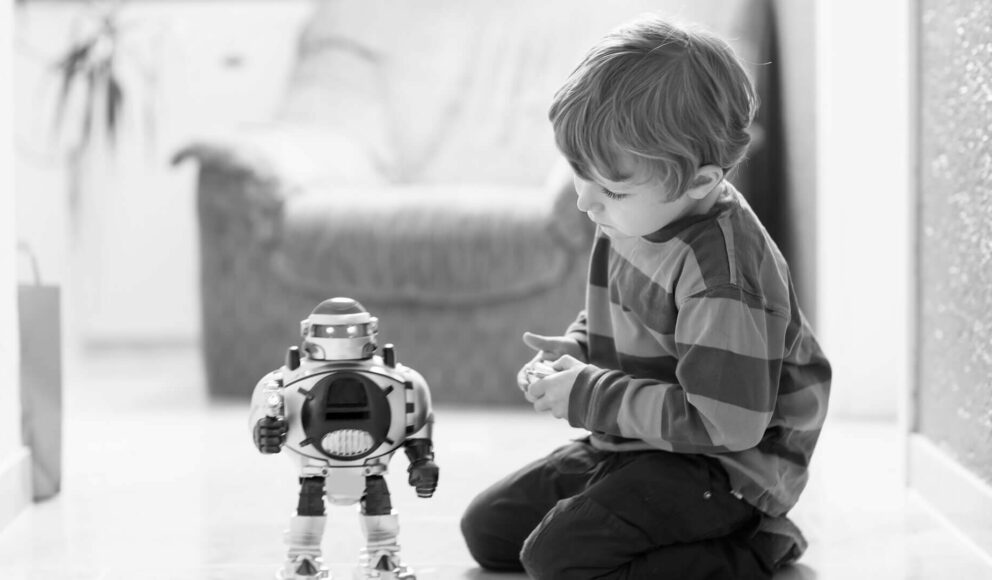 Black and white image of a child playing with a robot. AI hiring tools blog cover image.