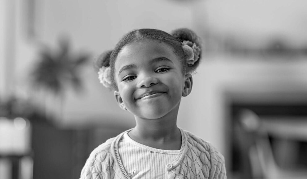 Black and white image of a child smiling at the camera. Cover image for the guide to building a purpose driven team blog.
