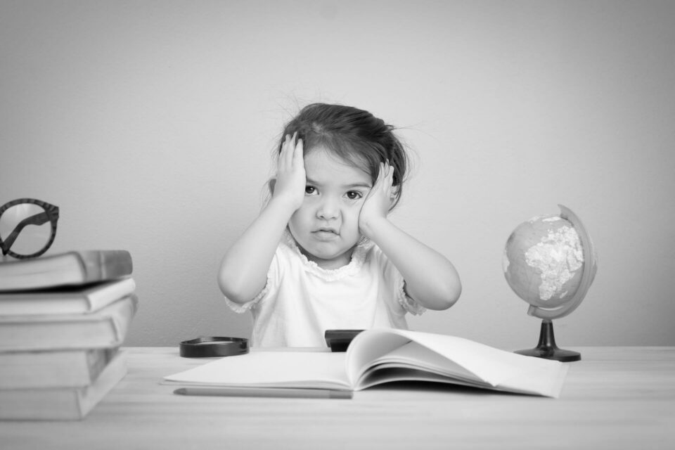 Black and white image of a girl looking confused whilst sitting at a desk. Cover image for the hiring strategy blog.
