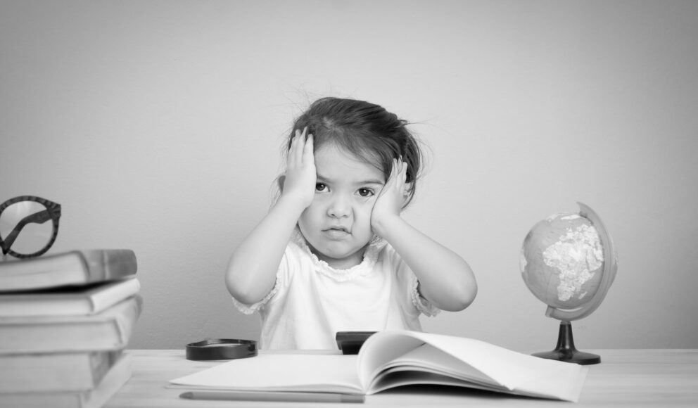 Black and white image of a girl looking confused whilst sitting at a desk. Cover image for the hiring strategy blog.