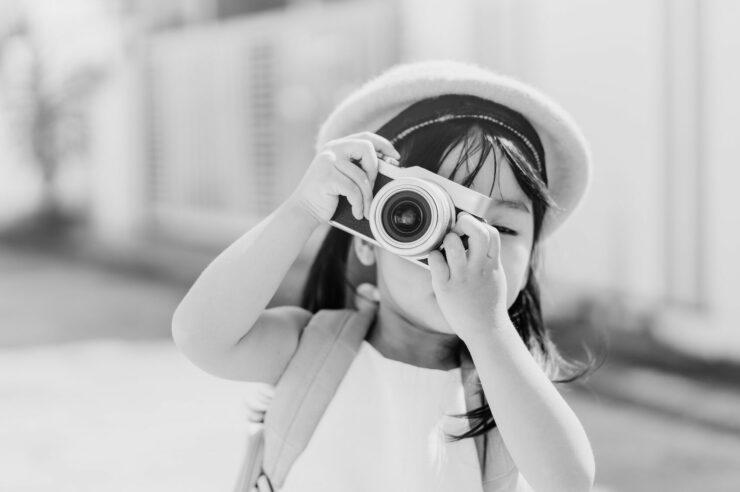 Black and white photo of a girl taking a photo. Cover image for the How to promote your EVP on social media blog.